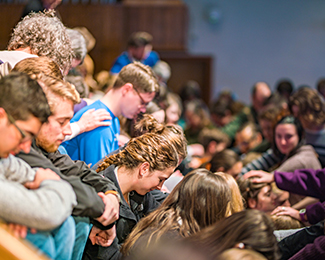 students praying for other students during convocation