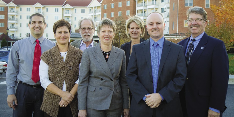 These current alumni working at Virginia Mennonite Retirement Community are standing on the shoulders of the EMU-linked persons who founded it in 1954 as the first modern retirement home in the area. From left: Mike Piper ’95; Diane Weaver ’91, MBA ’09; Marv Nisly ’68; Regina Schweitzer ’78, MBA ’07; Judith Trumbo ’82; Shawn Printz, MBA ’04; Les Helmuth ’78.