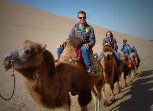 Riding camels in Dunhuang photo by Dylan Bomgardner
