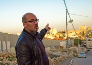 Husam Jubran, MA ’04, with Israel's "security fence" at left and the Aida refugee camp at right. Photo by Jon Styer