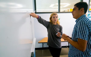 Student helping another student at a white board