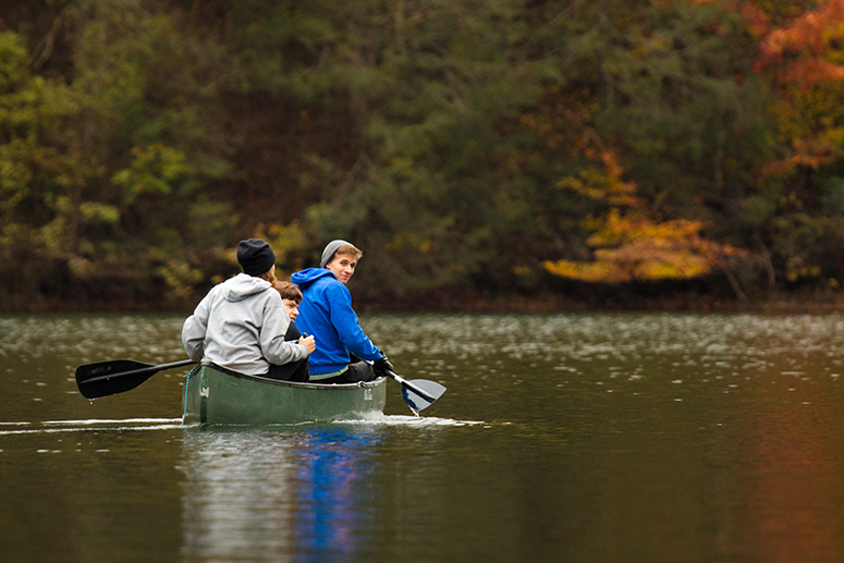 three students in a canoe in the mountains in the fall
