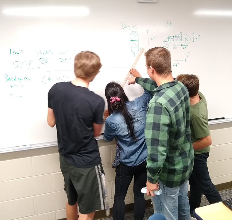 students working on a car diagram on a white board