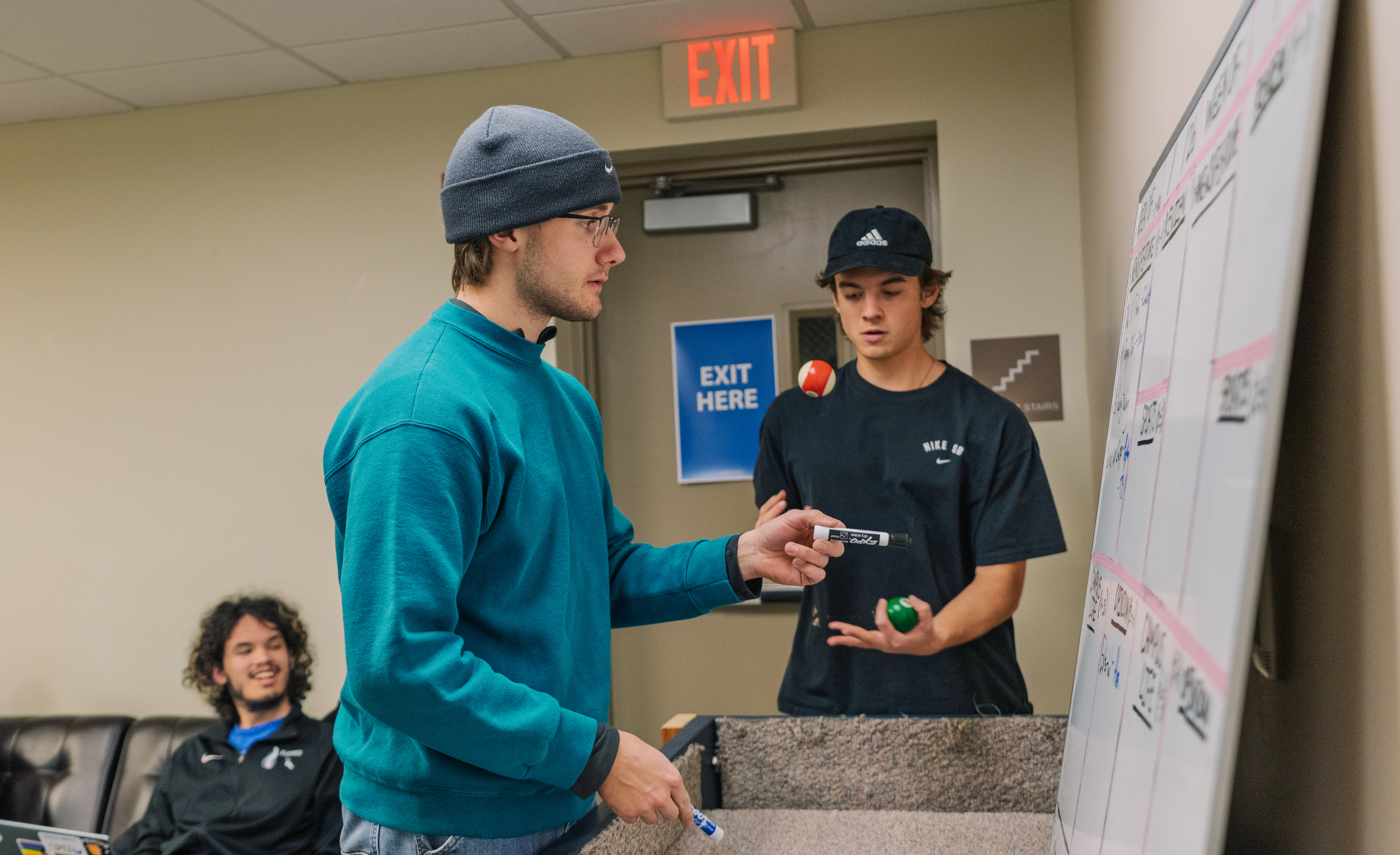 photo of 1 student adding to a drawing board and one student juggling