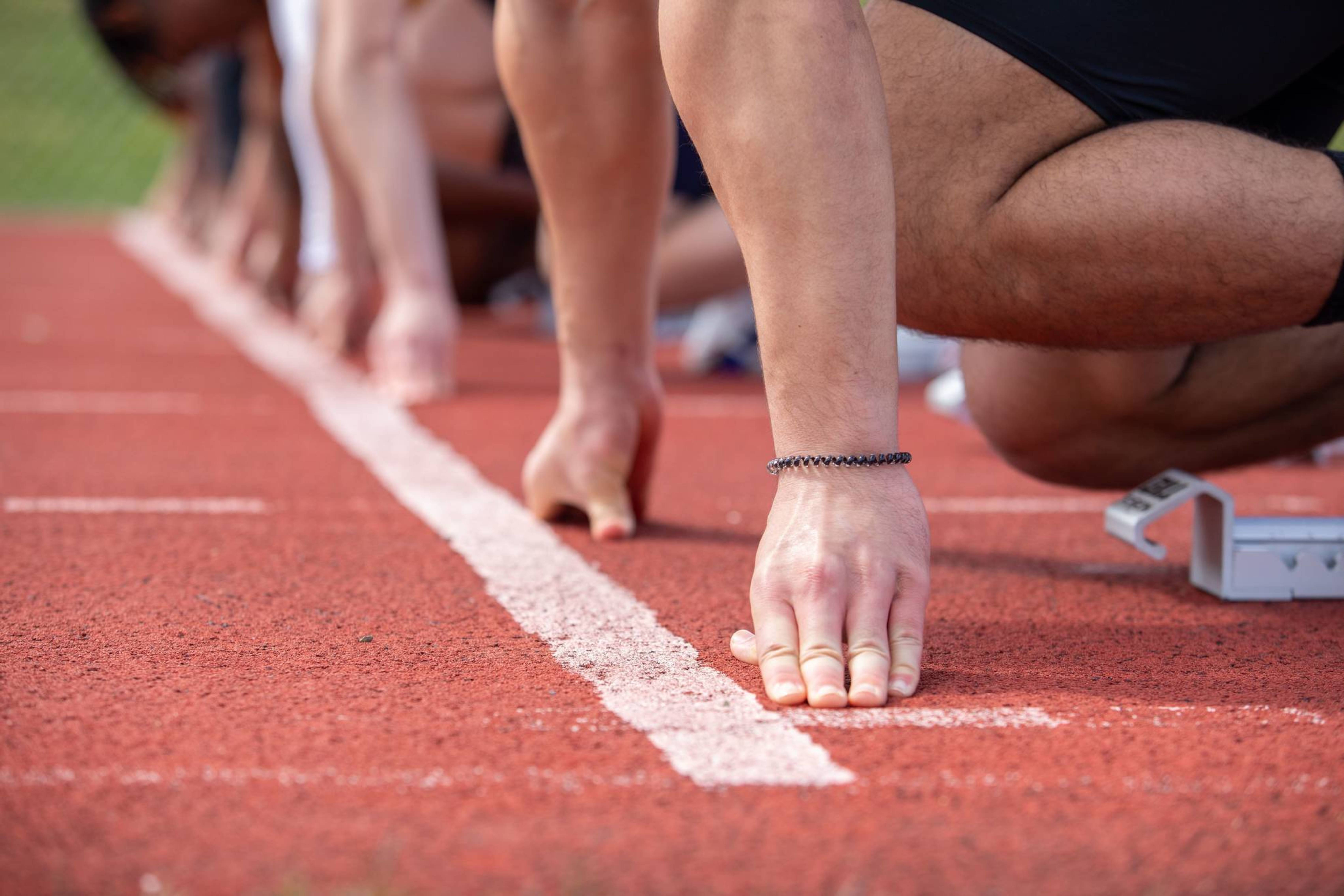hands positioned at the starting line on the outdoor track