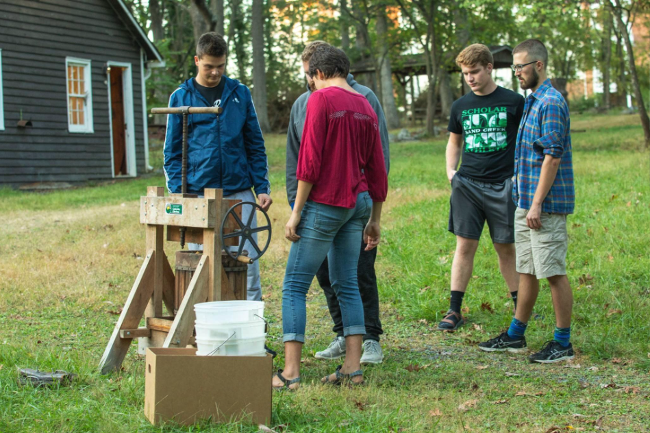 Students gathering in parkwoods to press apples for cider at a cider press