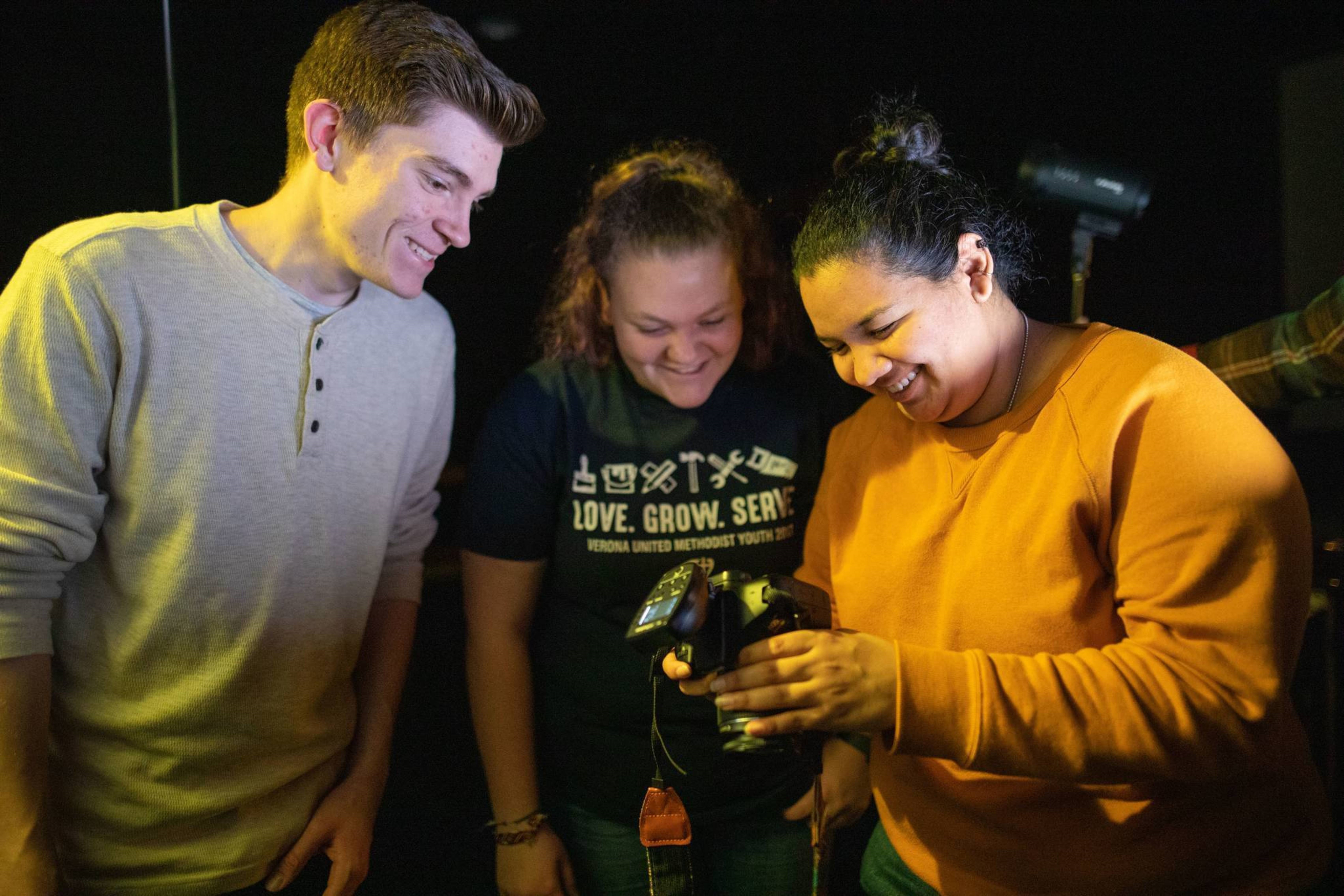 Three students looking at digital camera